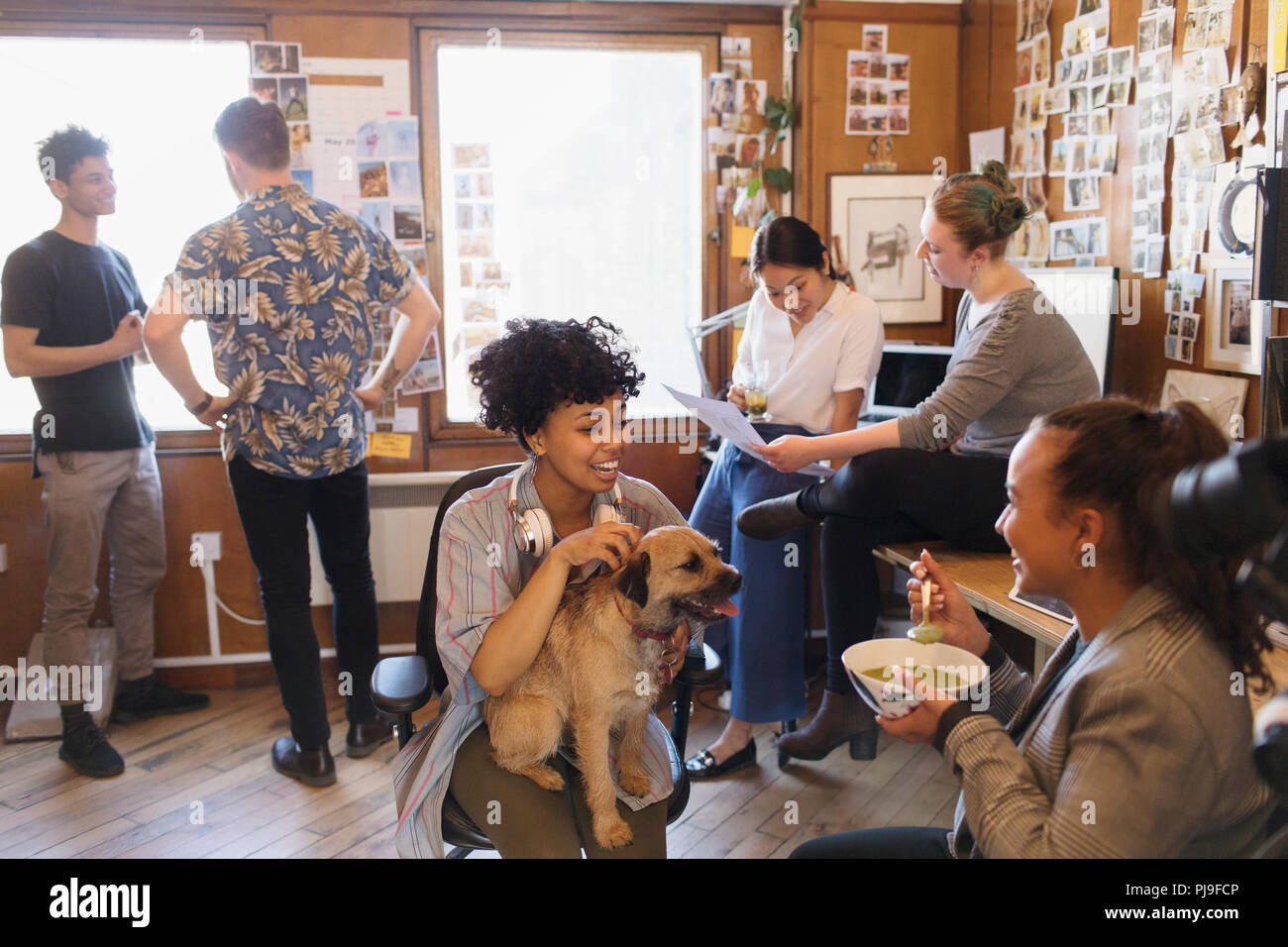 Creative business people with dog working and eating in office Stock Photo