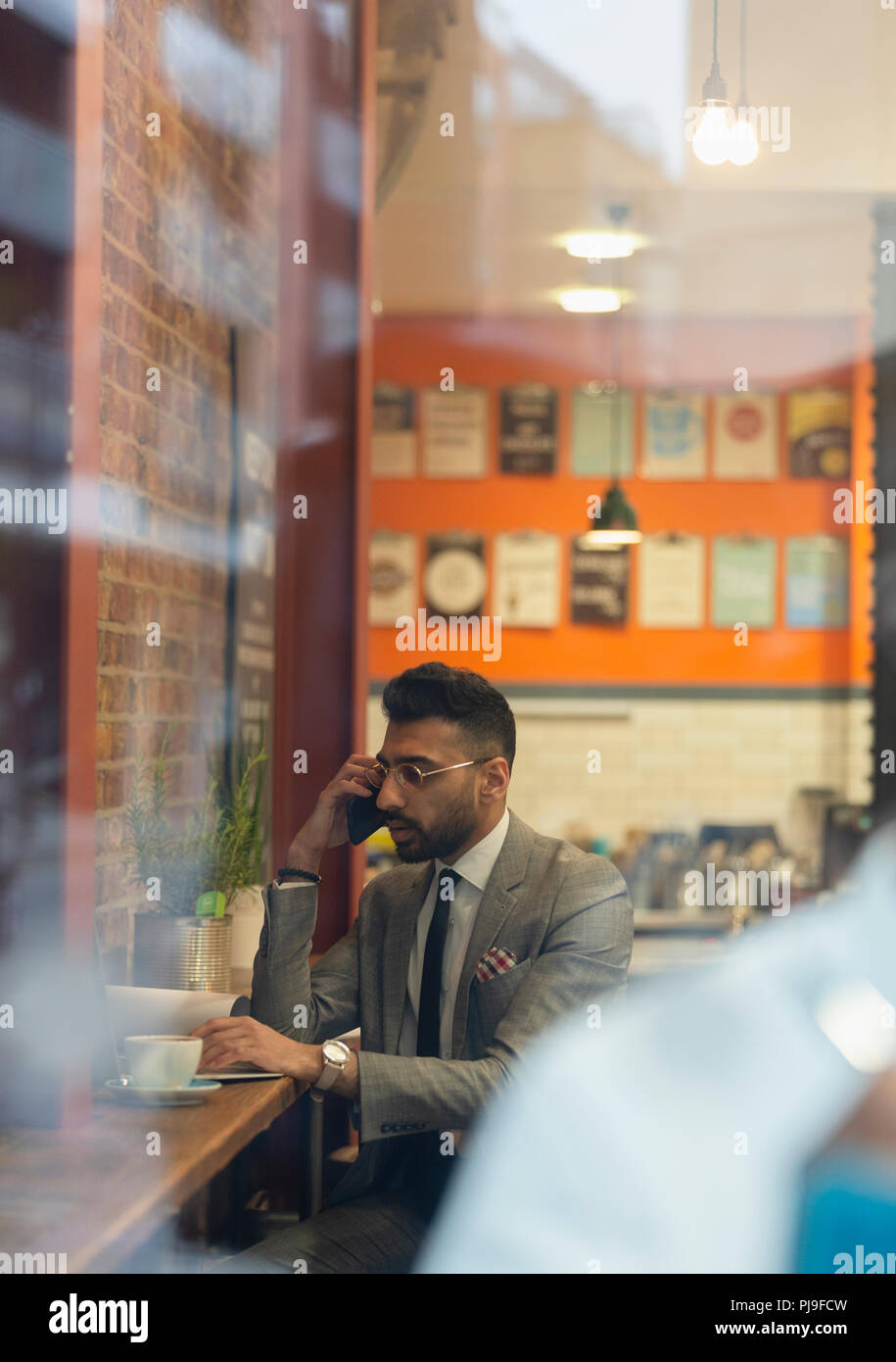 Businessman talking on smart phone, working in cafe Stock Photo