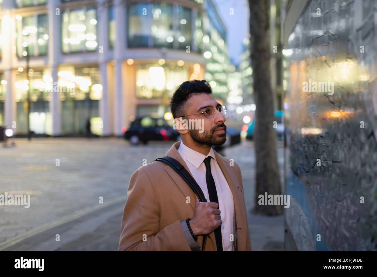 Businessman looking at city map on urban street at night Stock Photo