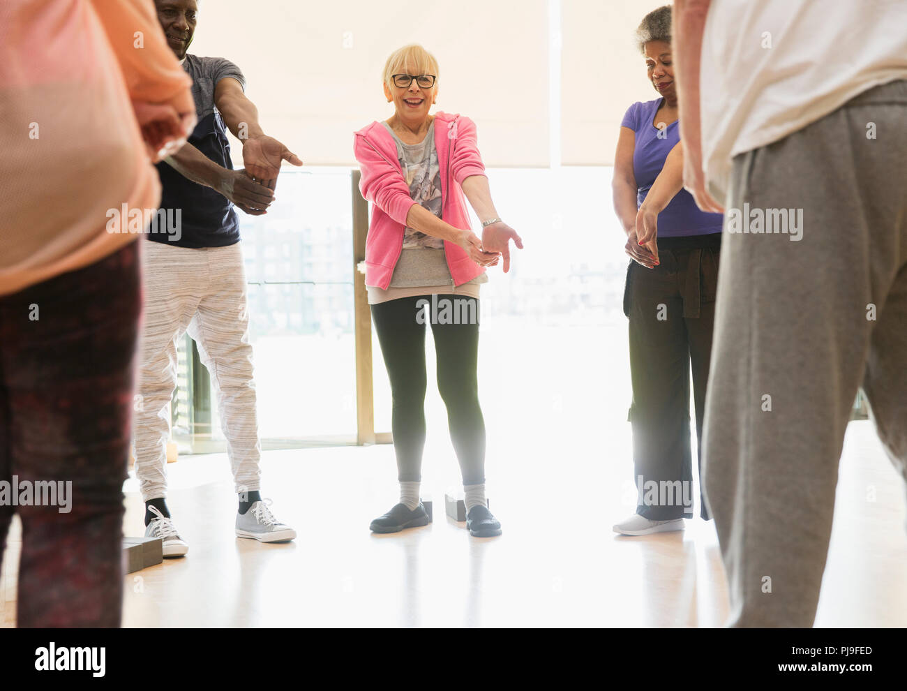 Active seniors stretching wrists in exercise class Stock Photo