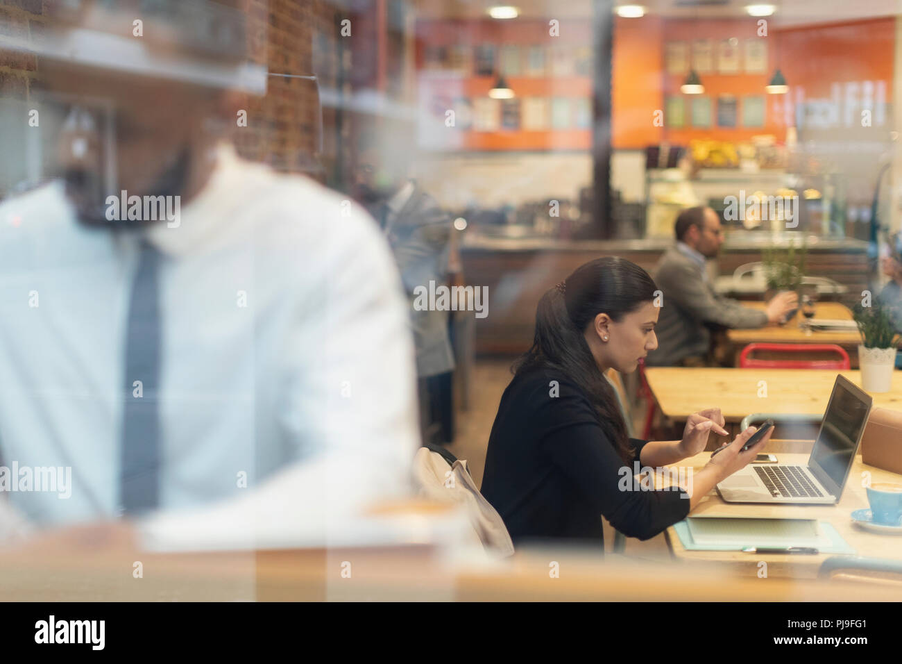 Focused businesswoman working at laptop in cafe Stock Photo