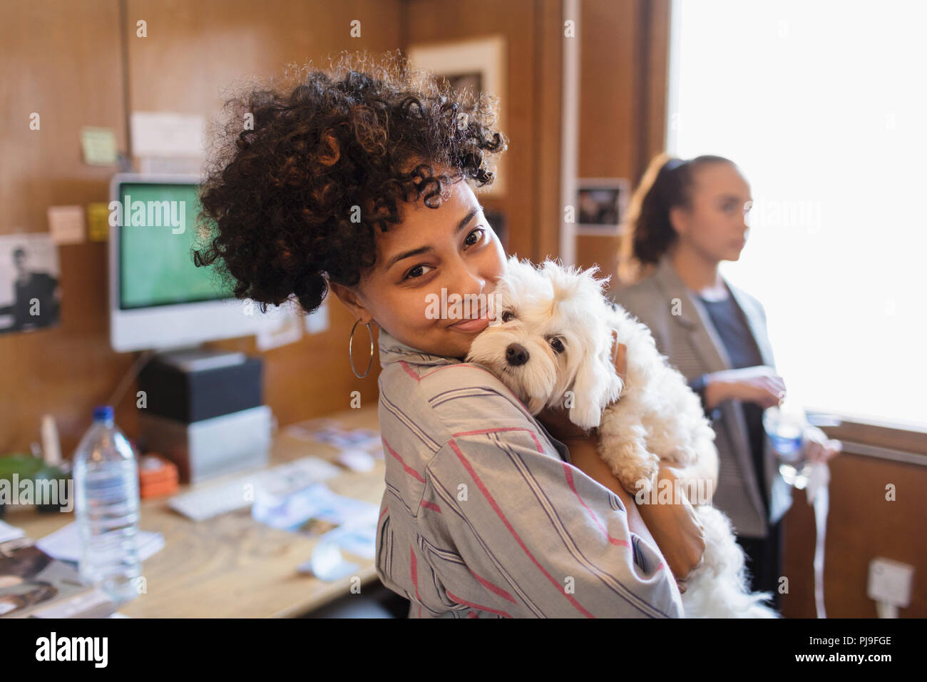 Portrait smiling creative businesswoman with cute dog in office Stock Photo