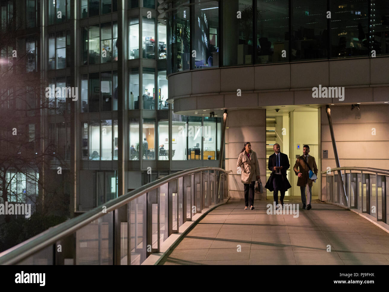 Business people walking on urban pedestrian bridge at night Stock Photo