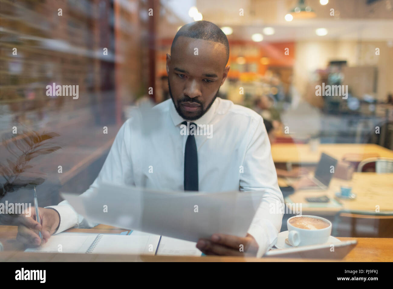 Focused businessman reviewing paperwork, working in cafe window Stock Photo
