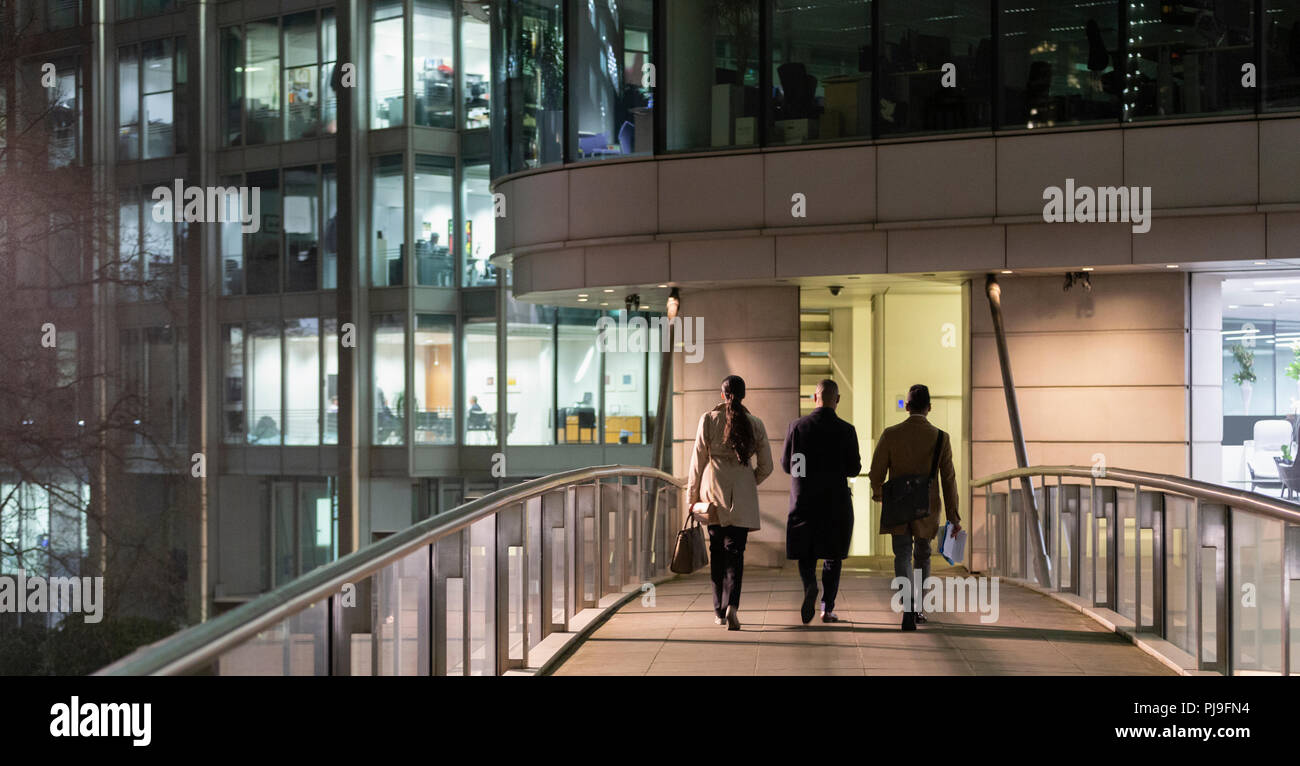 Business people walking on urban pedestrian bridge at night Stock Photo