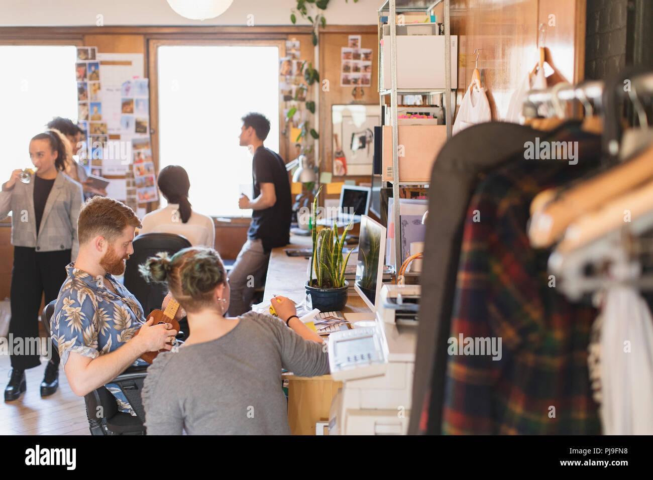 Creative designers working in office, playing ukulele Stock Photo Alamy