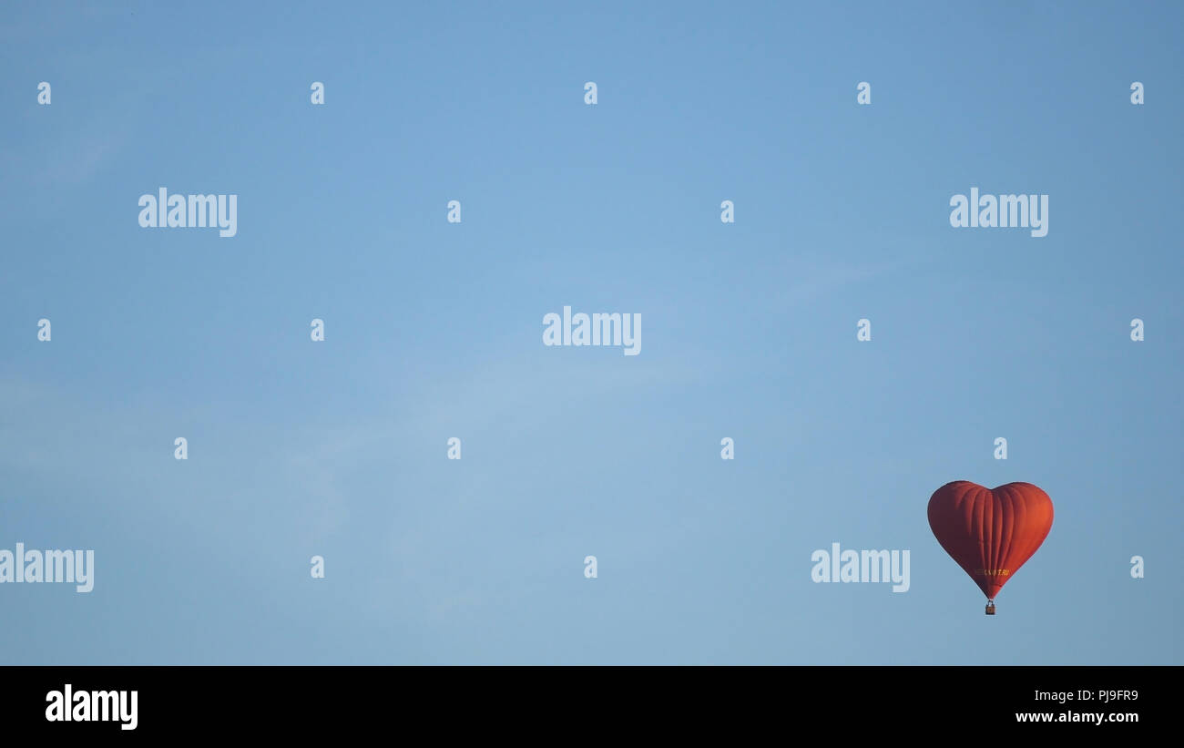 Hot air balloon shape of a heart in the blue sky. Aerostat, Airship ...