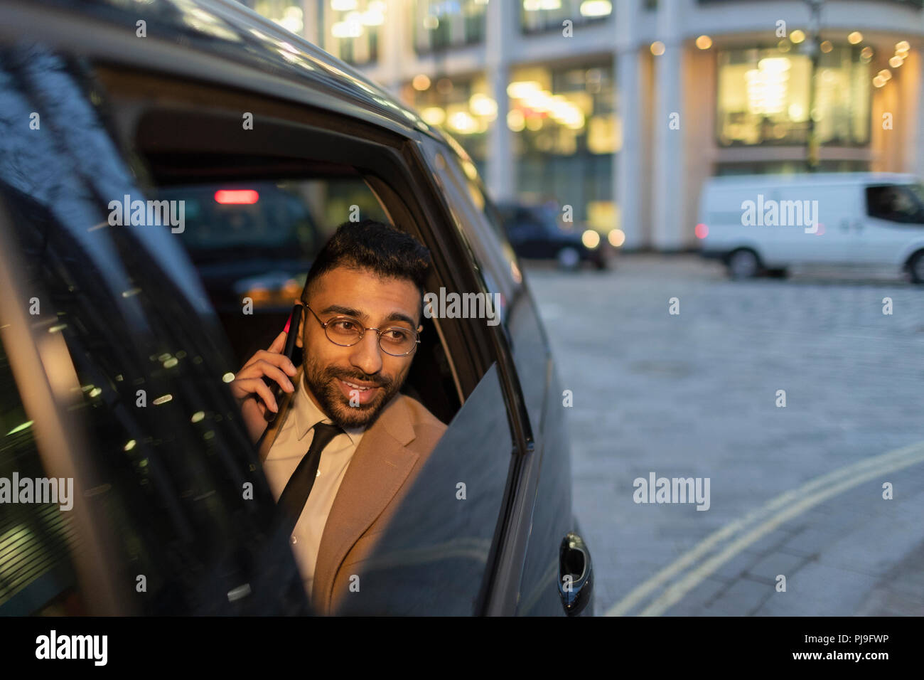 Businessman talking on smart phone in crowdsourced taxi Stock Photo
