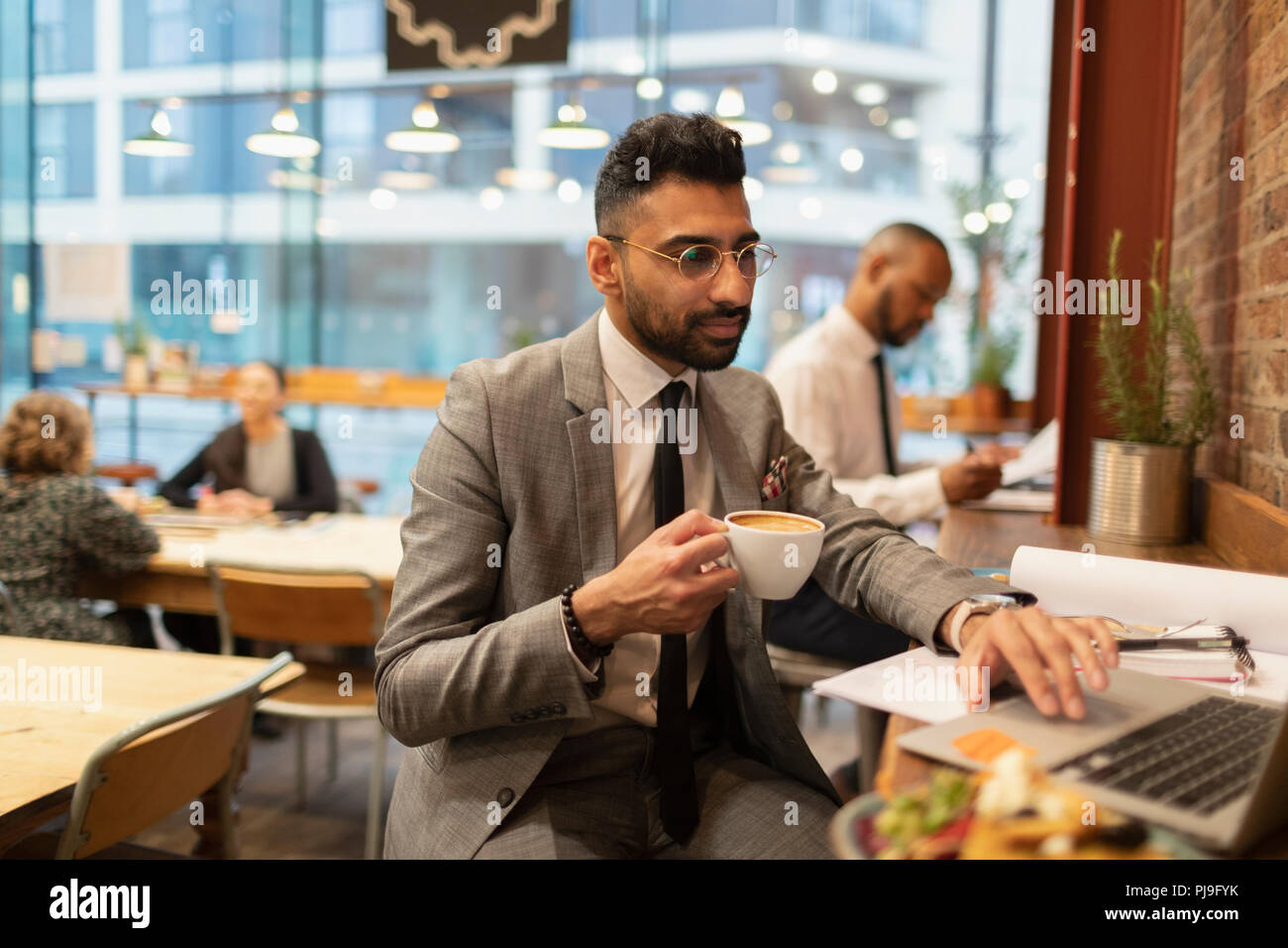 Focused businessman drinking coffee and working at laptop in cafe Stock Photo