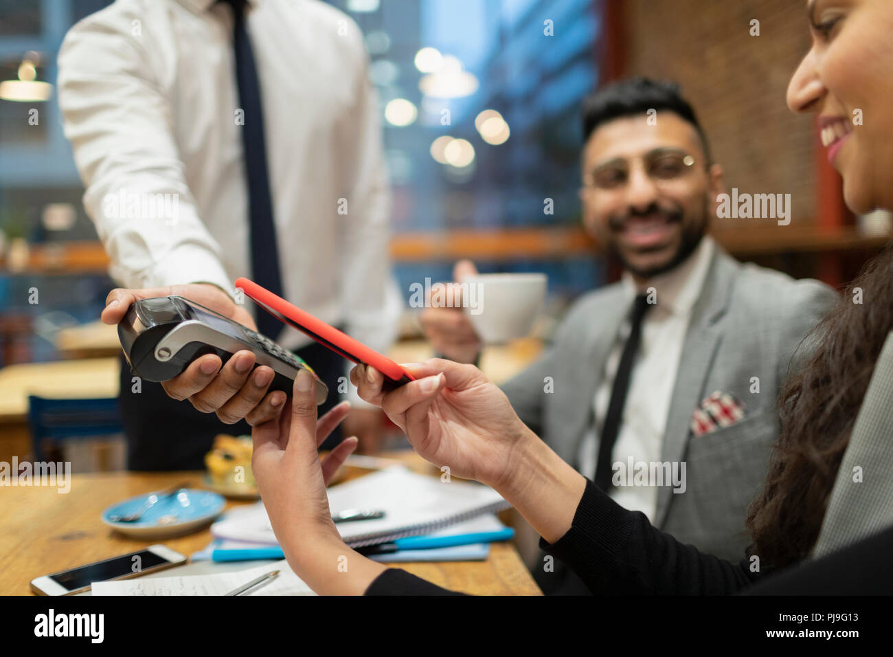 Businesswoman paying with smart phone contactless payment in cafe Stock Photo