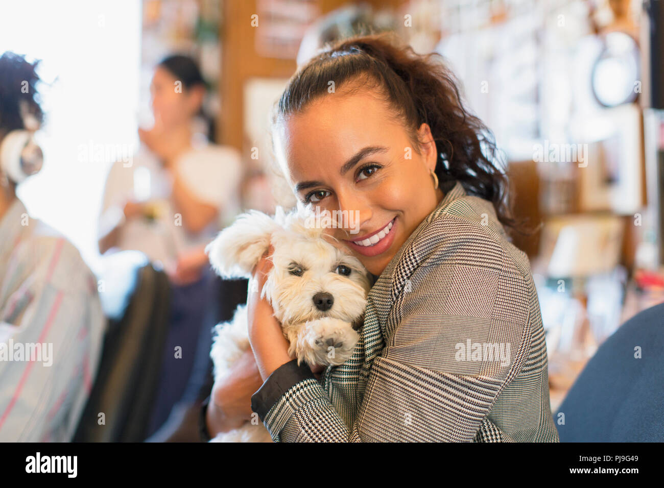 Portrait happy businesswoman with cute dog in office Stock Photo