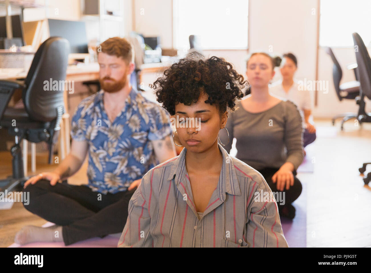 Serene creative business people meditating in office Stock Photo