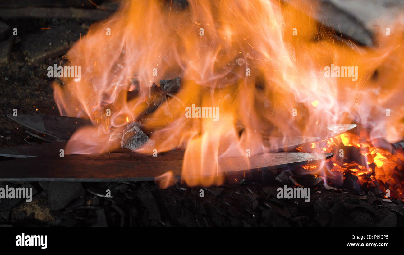 Blacksmith furnace with a hot iron, burning embers, sparks. Blazing