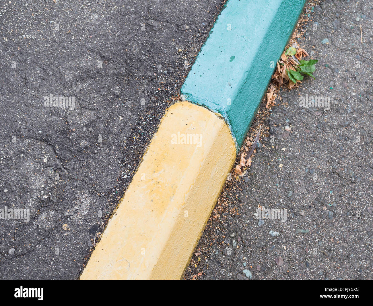 old green and yellow painted kerbstone on street Stock Photo