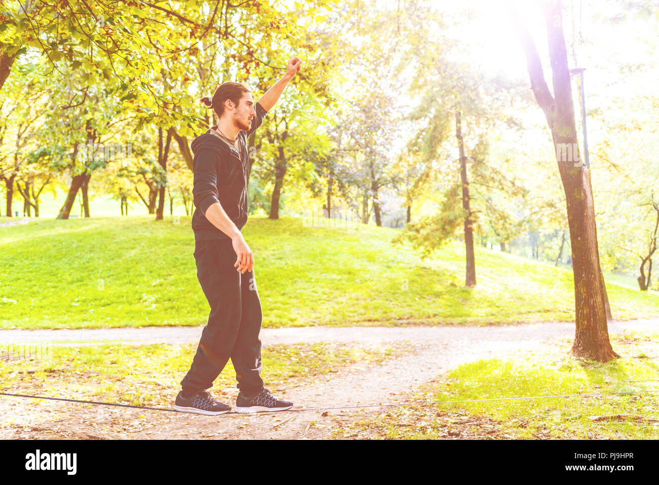 young man outdoor park slacklining - balance, sport, tightrope concept ...