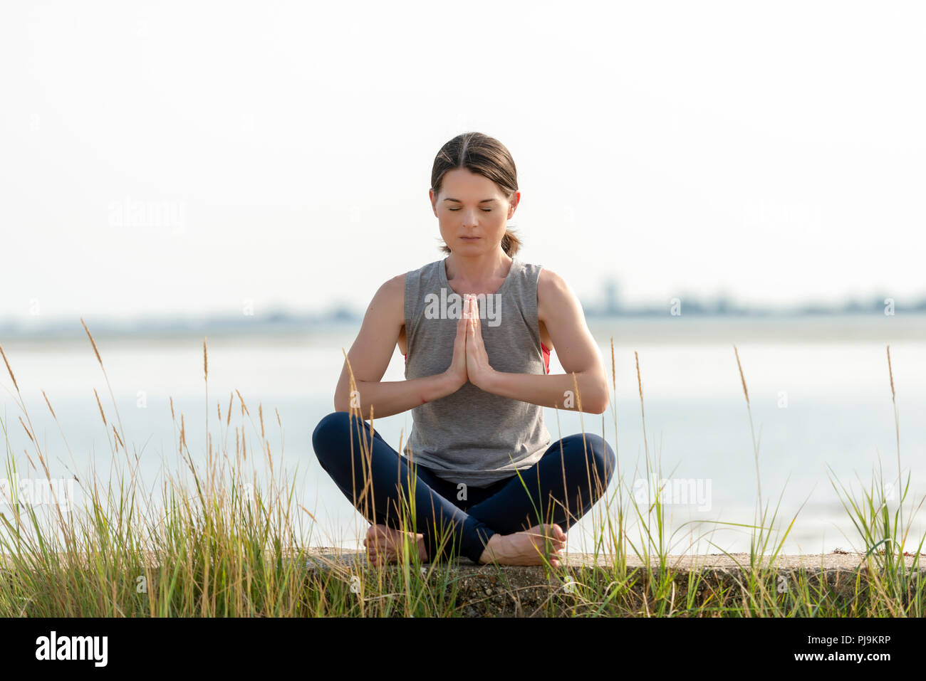 woman sitting crossed legged and meditating Stock Photo