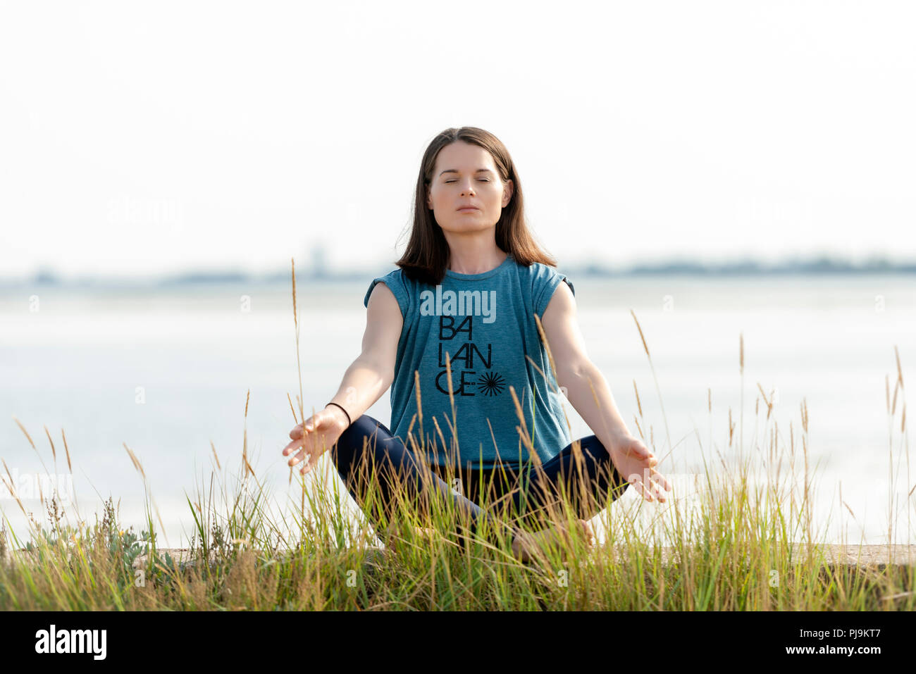 woman sitting crossed legged and meditating Stock Photo