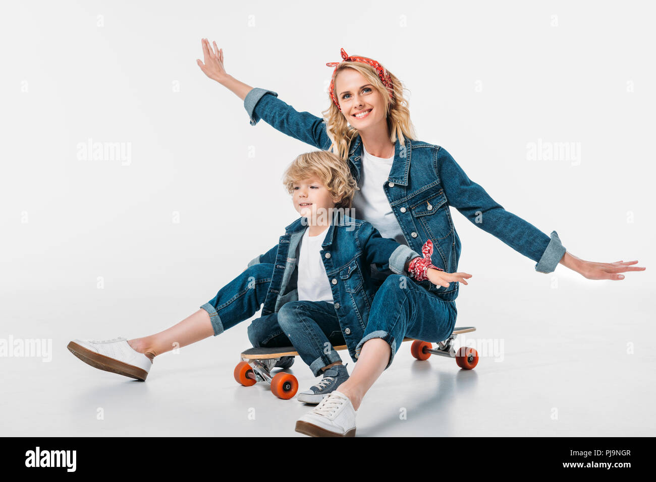 Happy Mother And Son Sitting On Skateboard And Pretending Flying