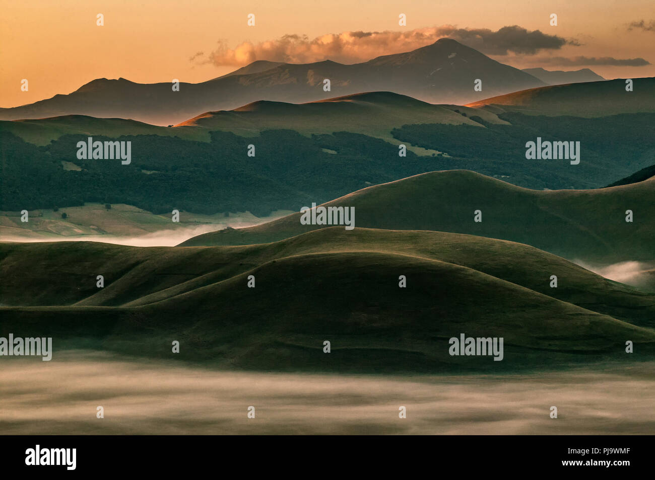 Panorama of the Sibillini Mountains with the morning mists illuminated by the red colors of dawn. Monti Sibillini National Park, Lazio, Italy, Europe Stock Photo