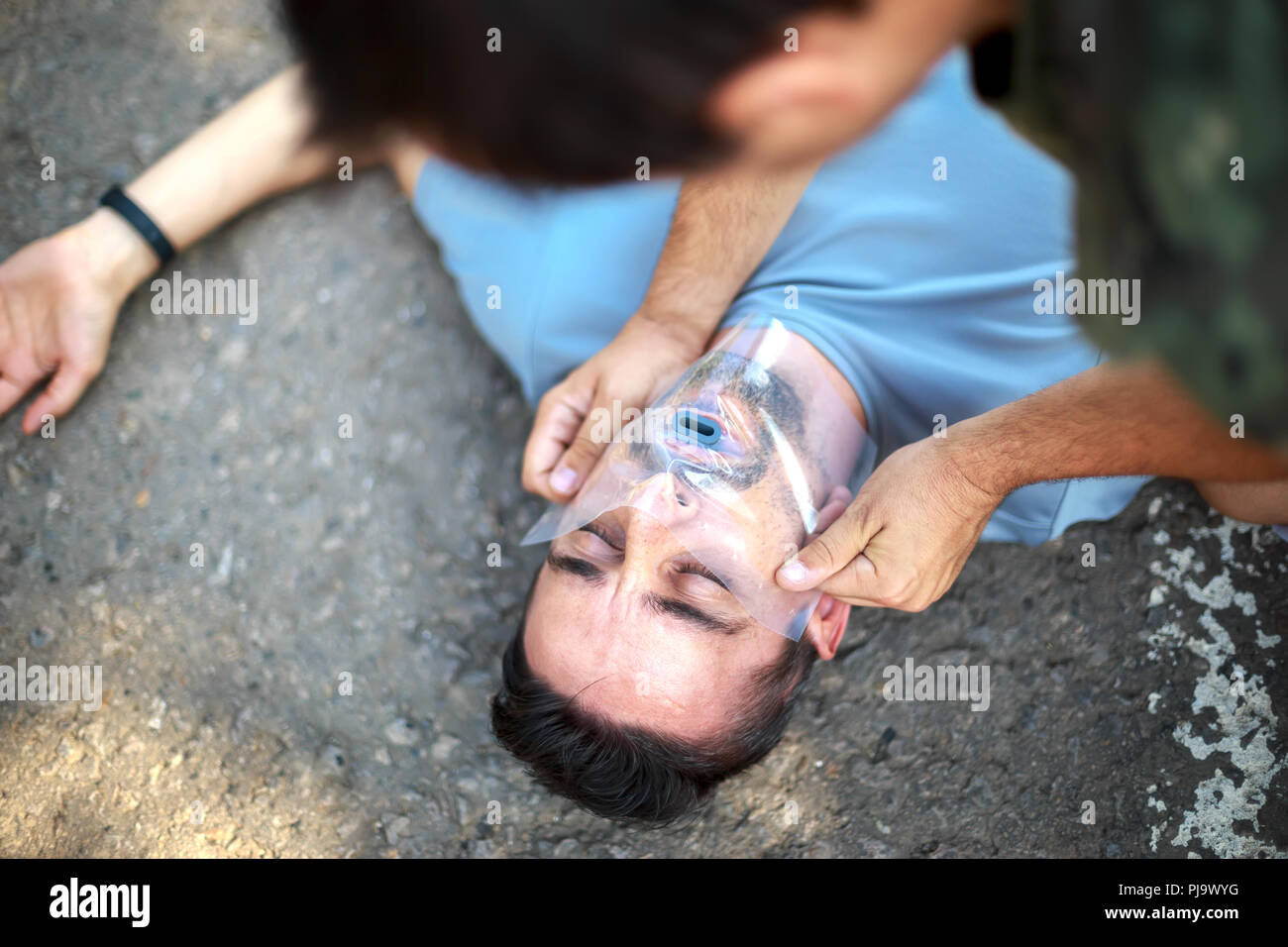 Man giving first aid to a person by using the savior's handkerchief. First Aid Stock Photo