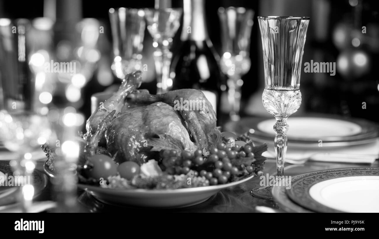 Black and white image of baked chicken on served festive dinner table Stock Photo
