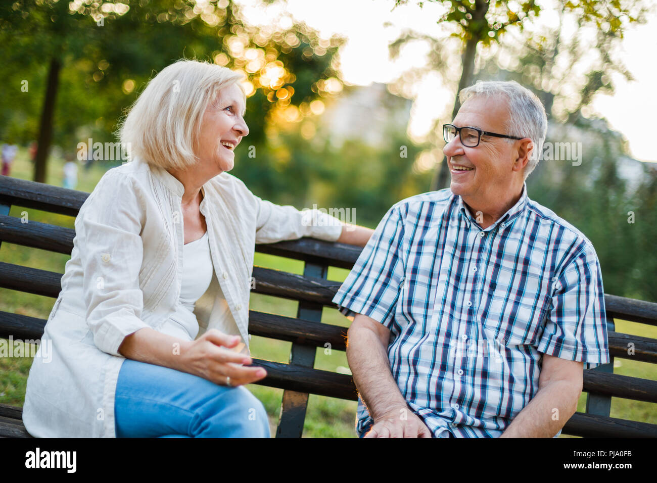 Two happy seniors are sitting and talking in park. Stock Photo
