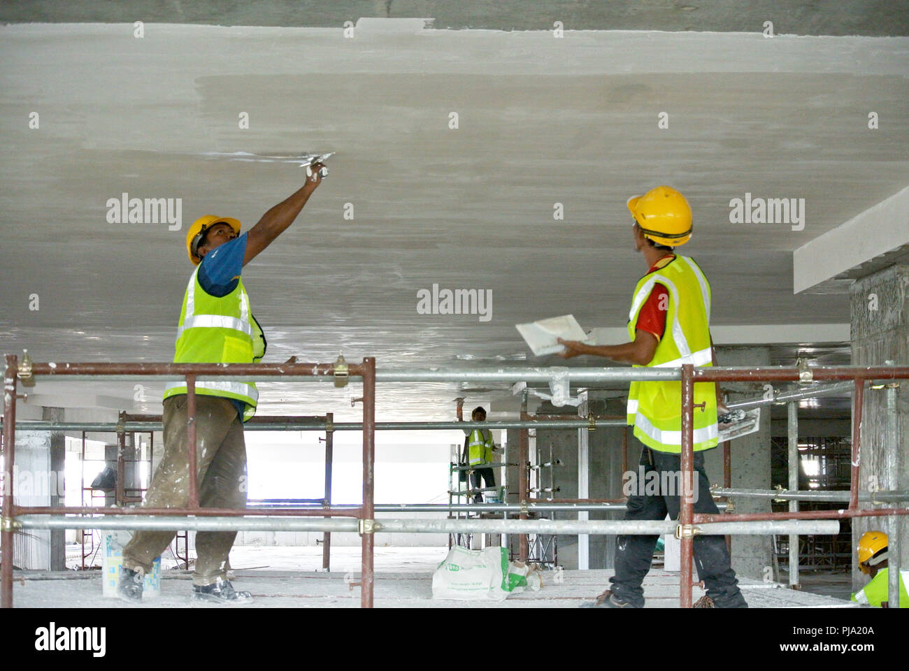 Construction site workers are doing ceiling soffit skim coat work at the construction site. Base and final coat layer apply to get the smooth surface. Stock Photo