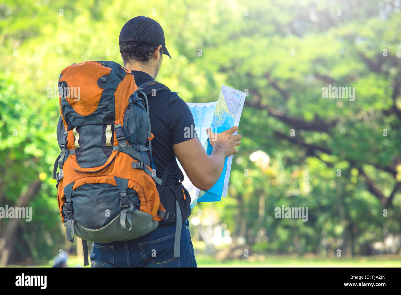 Man backpacker in vacations looking at map in nature Stock Photo