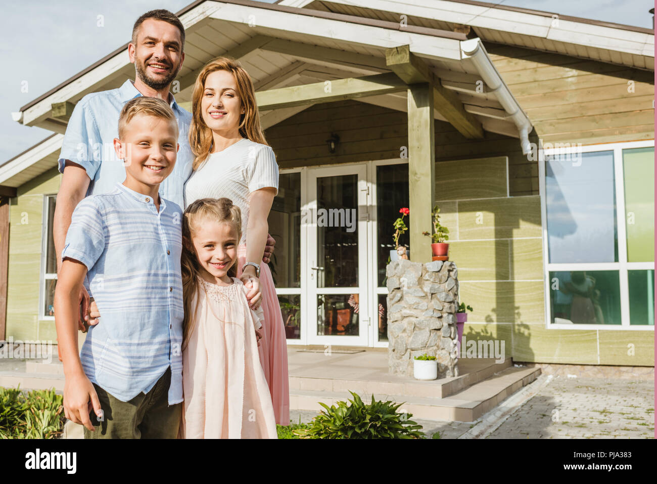 smiling parents and children standing in front of house Stock Photo