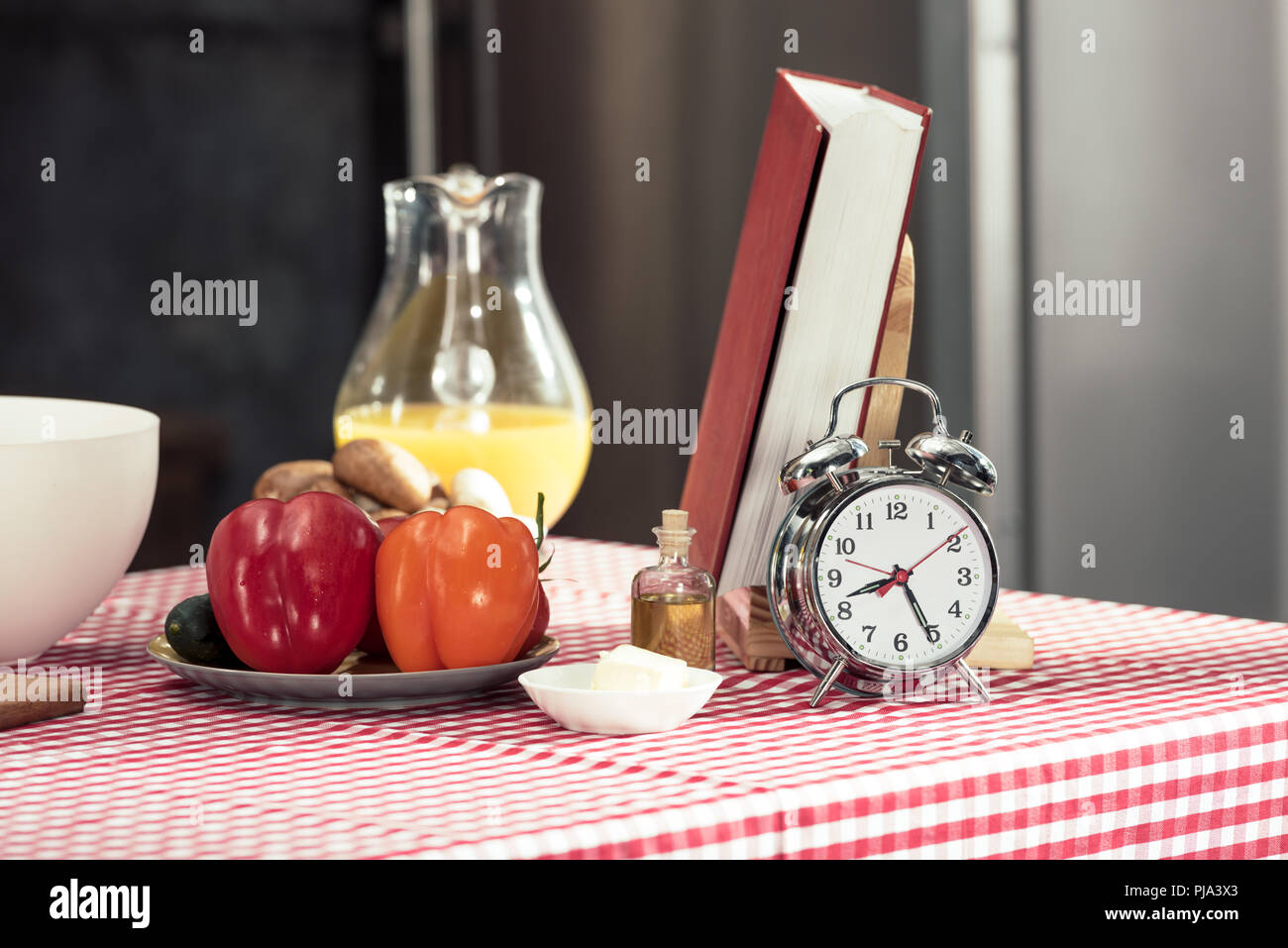 vintage alarm clock with various products and recipe book on table Stock Photo