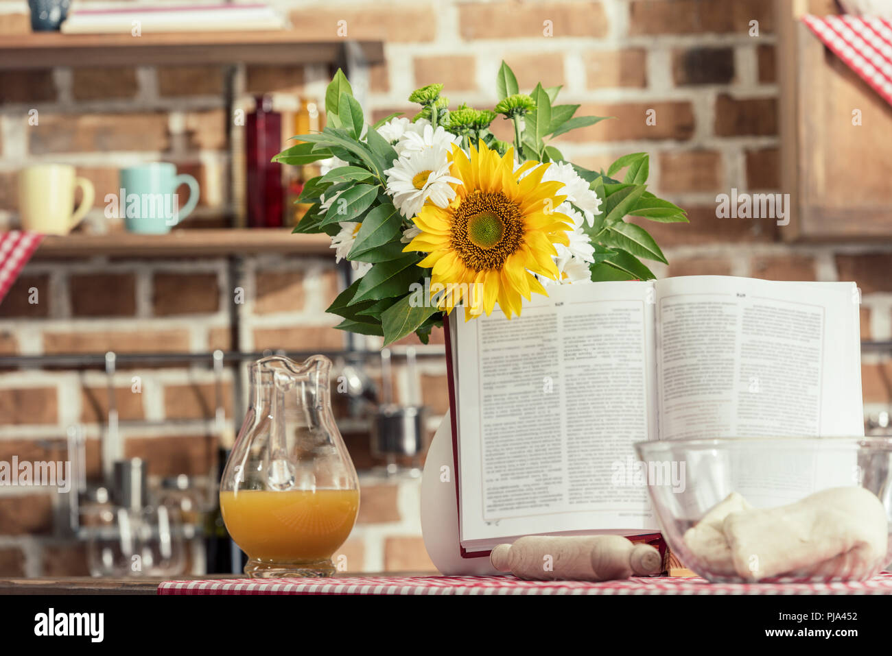 recipe book and bouquet of flowers on cooking table at kitchen Stock Photo
