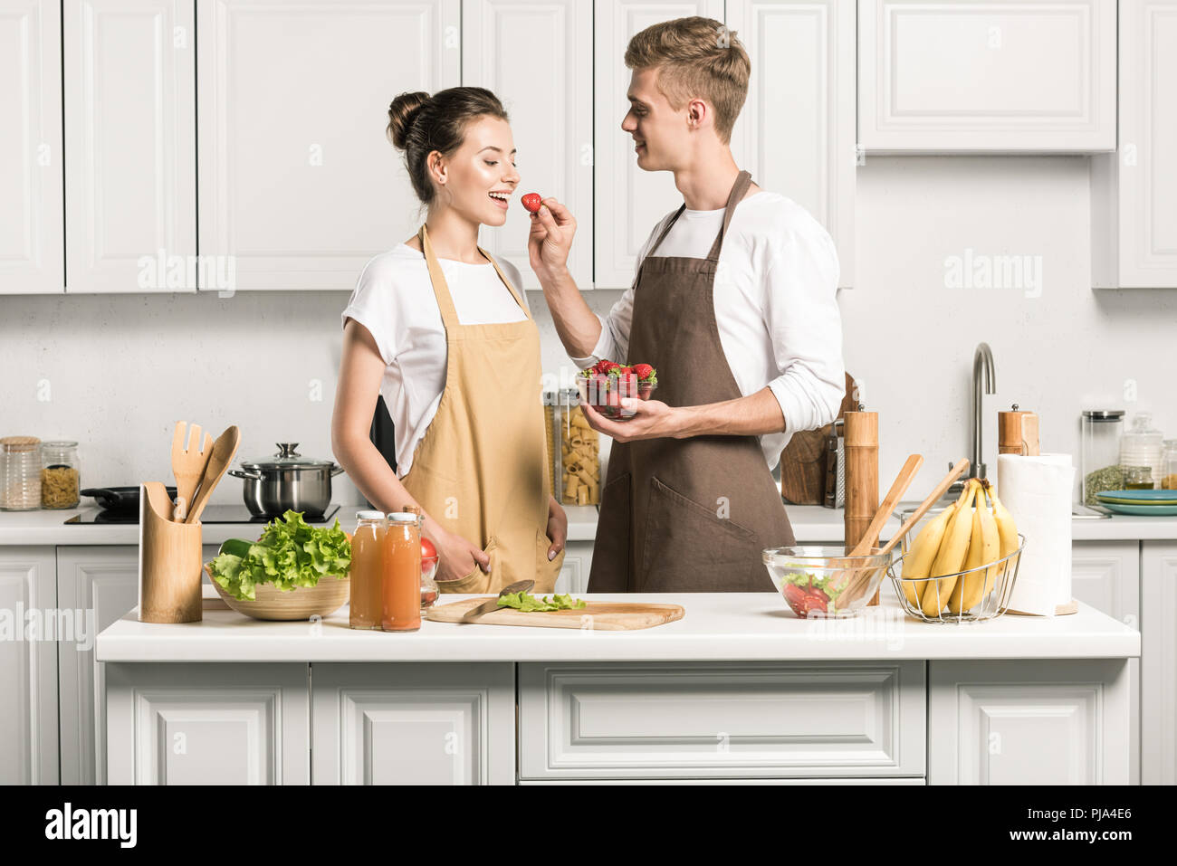 boyfriend feeding girlfriend with strawberry in kitchen Stock Photo Alamy