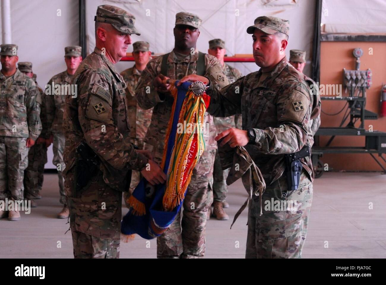 ERBIL, Iraq - U.S. Army 4th Attack Reconnaissance Battalion, 4th Aviation Regiment Commander Lt. Col. Tim Jaeger (left) and Command Sgt Maj. Ruben Davila unfurl their battalion colors during a transfer of authority ceremony June 24, 2018.  The ceremony signified the assumption of command of the mission to provide enabling support to Coalition and partner forces in the defeat-ISIS mission in support of Operation Inherent Resolve. Stock Photo