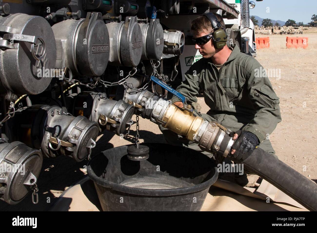 Army Reserve Spc. Joseph K. Reinhard, a petroleum specialist with the 900th Quartermaster Company based in El Paso, Texas, monitors the flow of  JP-8 jet fuel as 14,000 gallons of fuel is pumped from a tanker into a 20,000 gallon collapsible tank at a refueling point, July 5, 2018 at Fort Hunter Liggett, California. The 900th QM is at Fort Hunter Liggett for a training mission in support of Combat Support Training Exercise  (CSTX) 91-18-01, an exercise conducted by the Army Reserve’s 91st Training Division. (Arizona Army National Guard Stock Photo