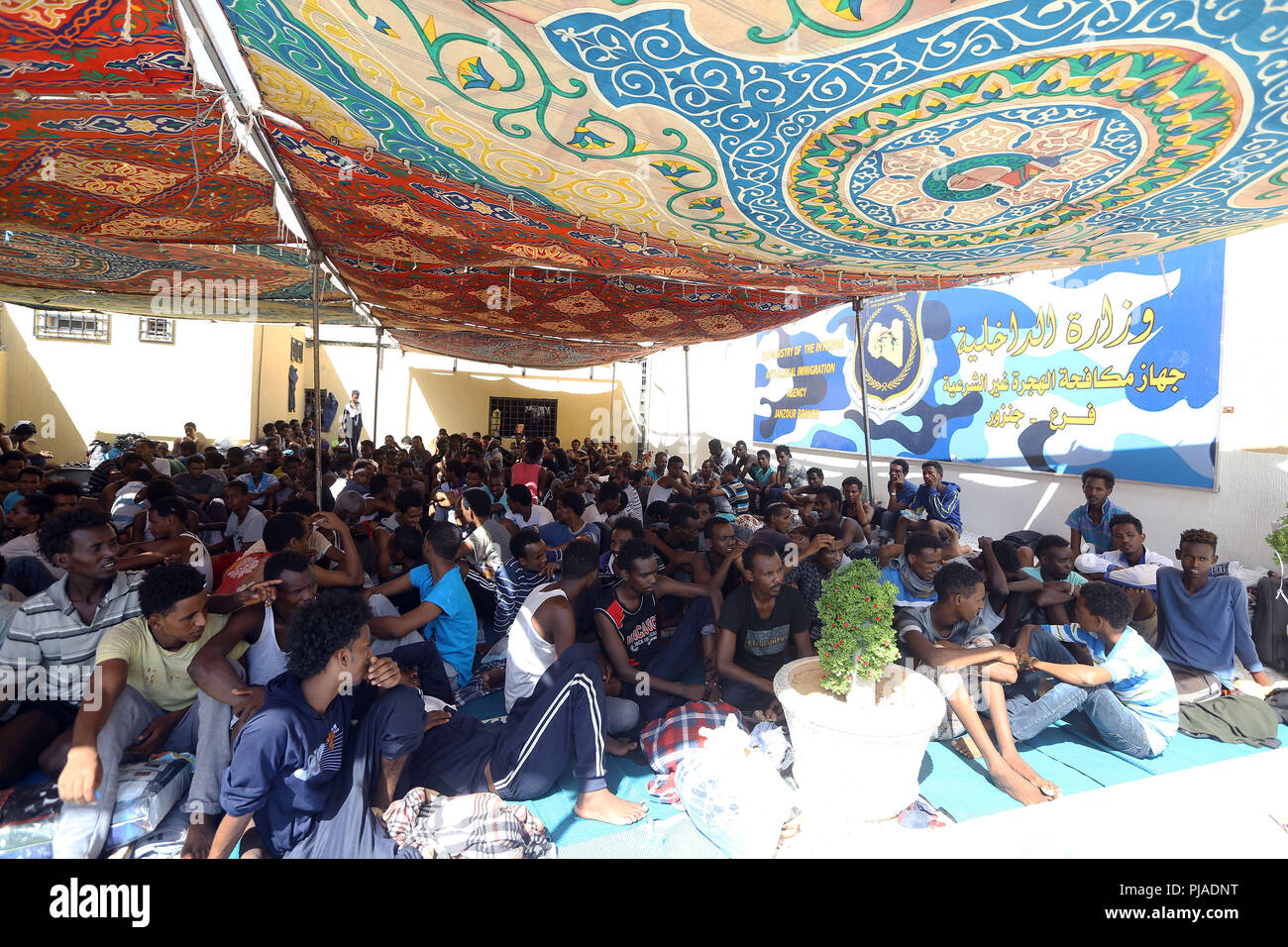 Tripoli. 5th Sep, 2018. Illegal migrants sit inside the Ganzour shelter after being transferred from another shelter near the airport due to clashes in Tripoli, Libya, Sept. 5, 2018. The UN Support Mission in Libya (UNSMIL) on Tuesday announced that the fighting parties in the capital Tripoli have signed a UN-sponsored agreement to end the fierce fighting in the city. Credit: Xinhua/Alamy Live News Stock Photo