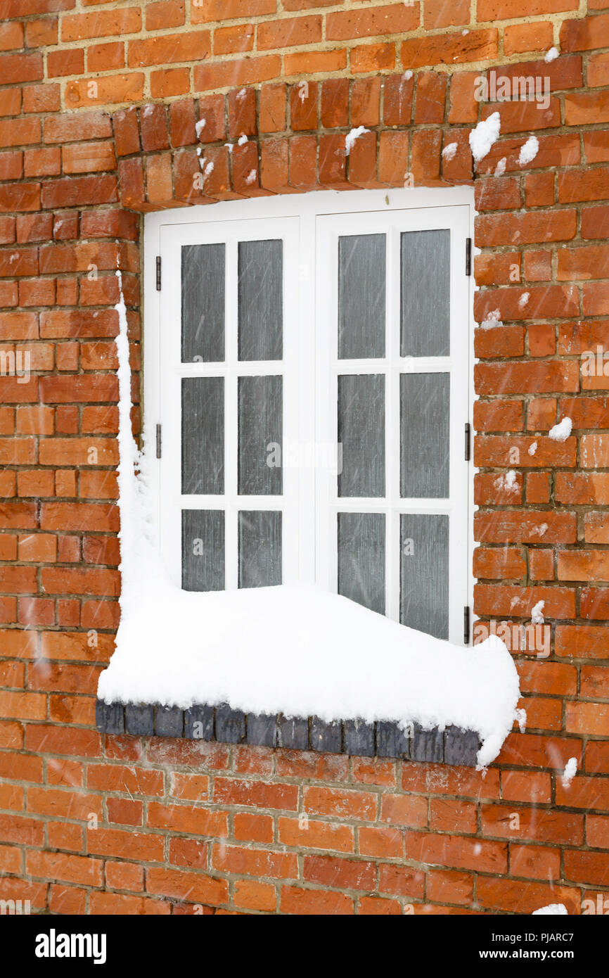 Snow in winter covers the window of an old brick house in England Stock Photo