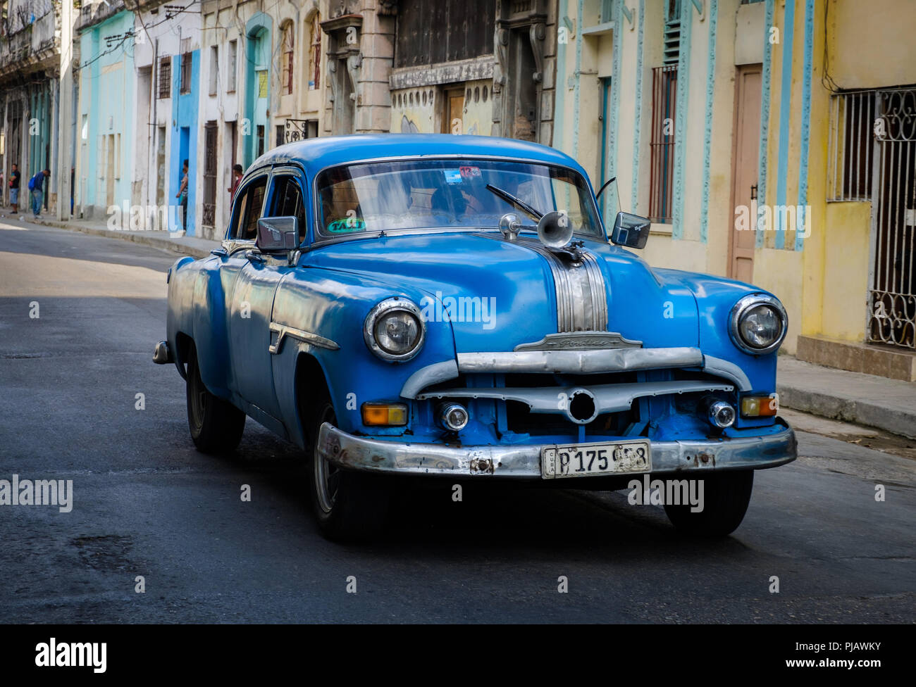 HAVANA, CUBA - CIRCA MARCH 2017: Old car drives in the streets of Havana, passing by a colorful home. Stock Photo