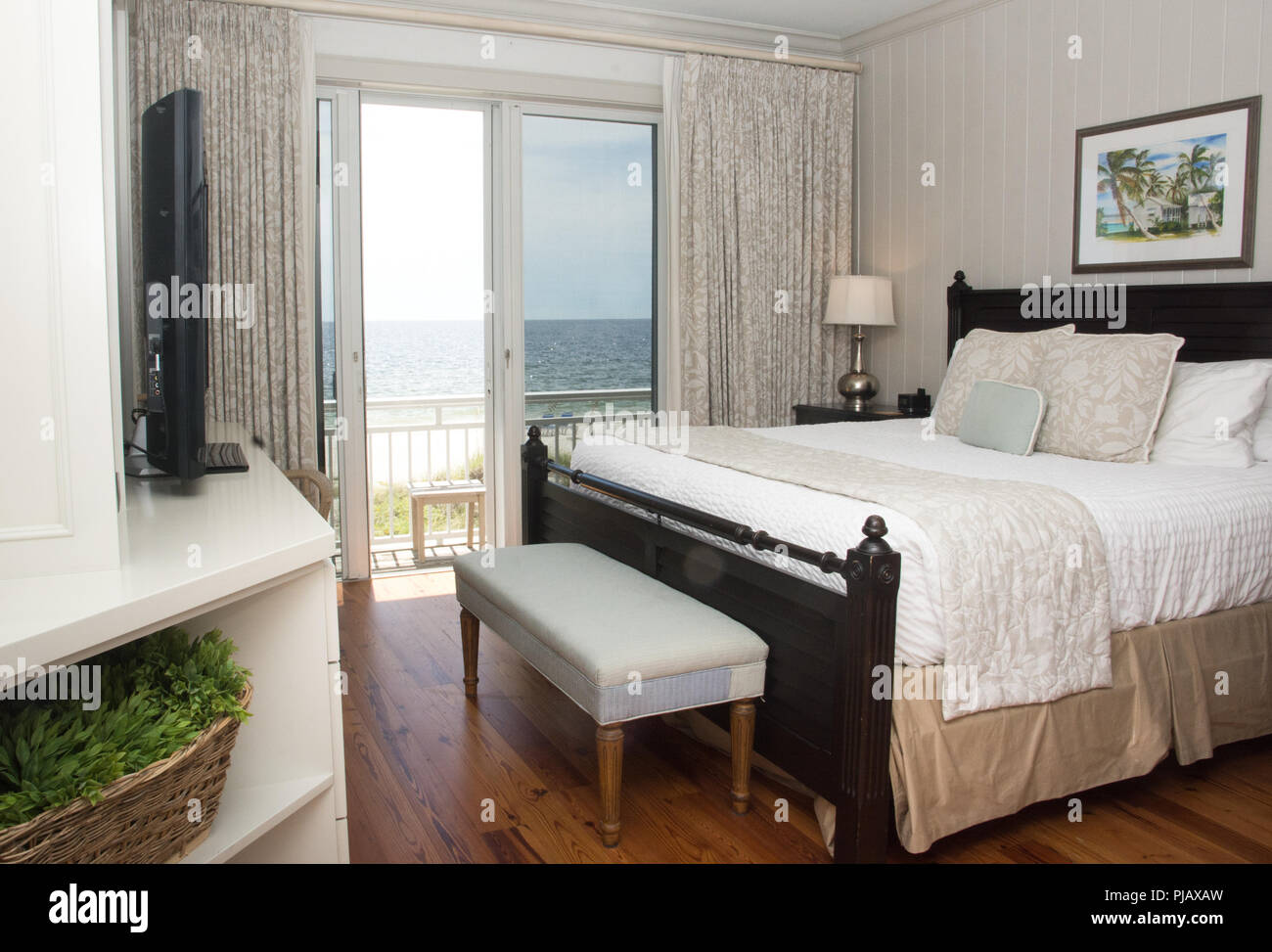 An interior shot of a bedroom with a balcony that overlooks the ocean. Stock Photo