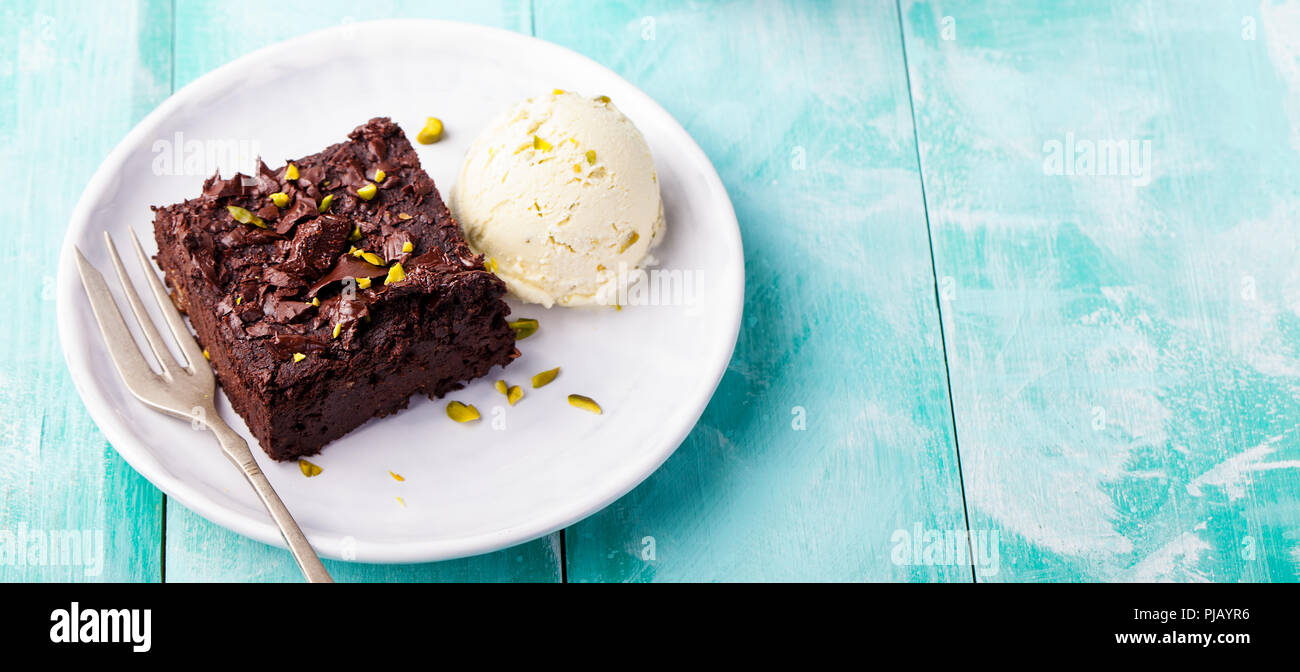 Chocolate brownie, cake on a white plate on a turquoise wooden background. Copy space. Stock Photo