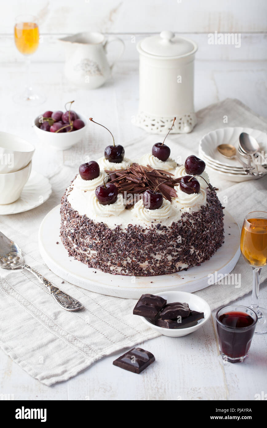 Black forest cake, Schwarzwald pie, dark chocolate and cherry dessert on a white wooden cutting board. Stock Photo