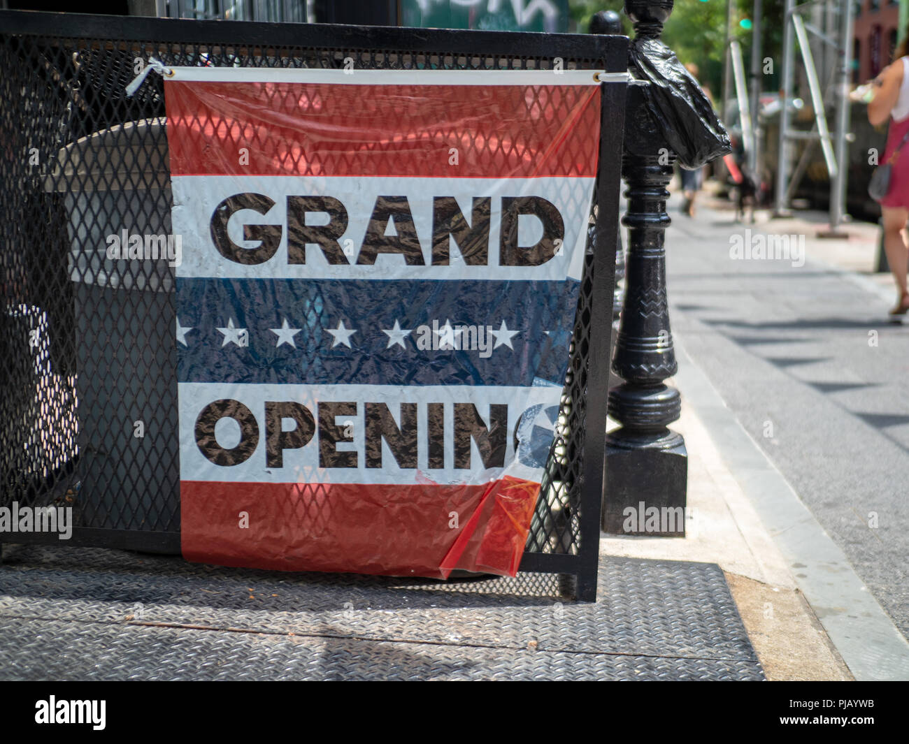 Makeshift grand opening sign hanging outside storefront on street  Stock Photo