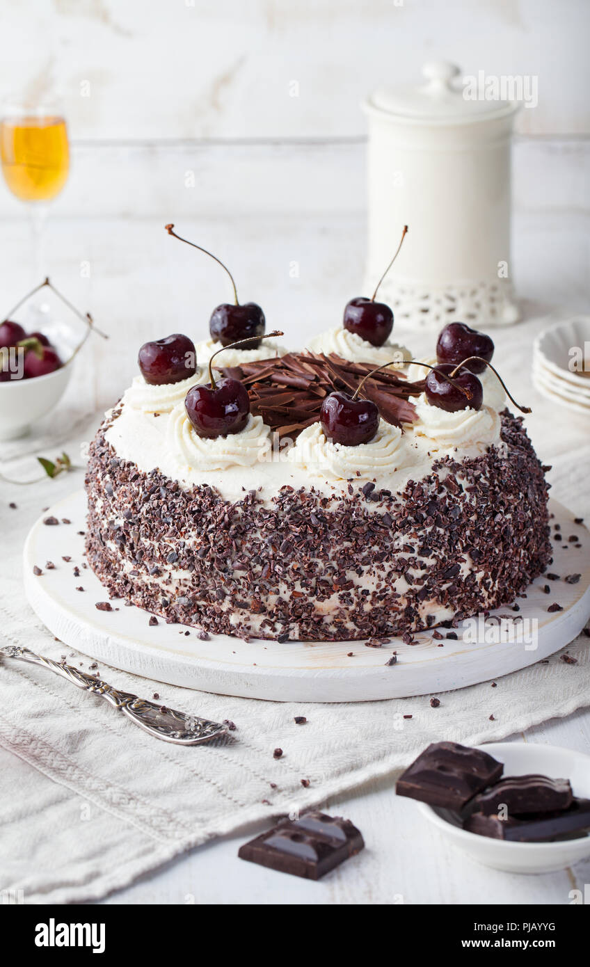 Black forest cake, Schwarzwald pie, dark chocolate and cherry dessert on a white wooden cutting board. Stock Photo