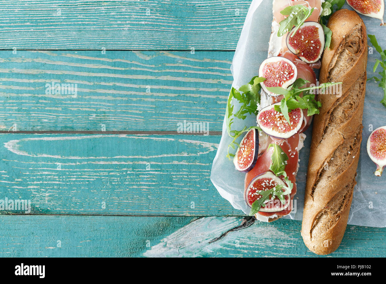 Sandwich with prosciutto, mascarpone cheese and figs on wooden table with border top view Stock Photo