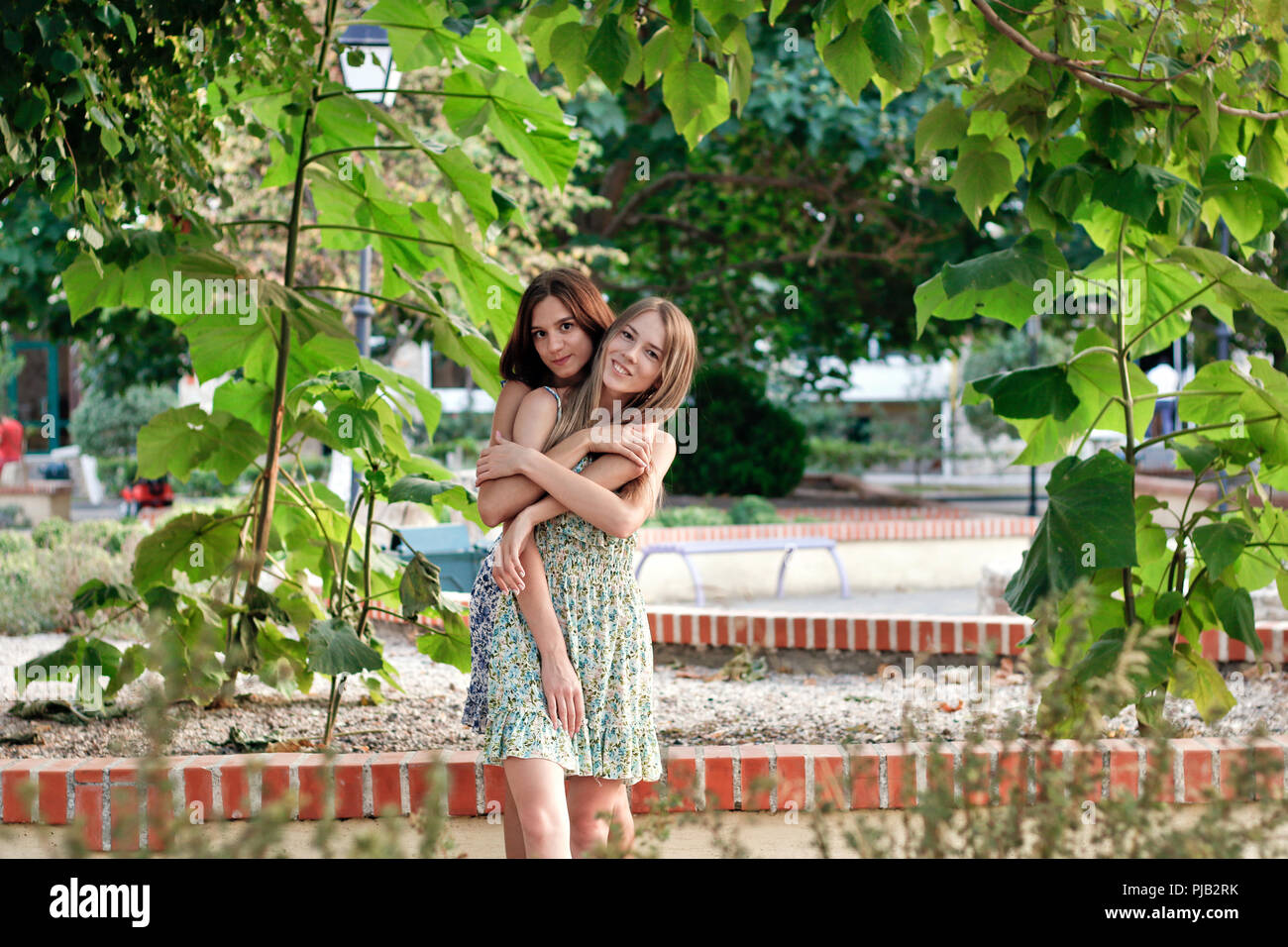 two cute girls holding each other in the garden Stock Photo Alamy