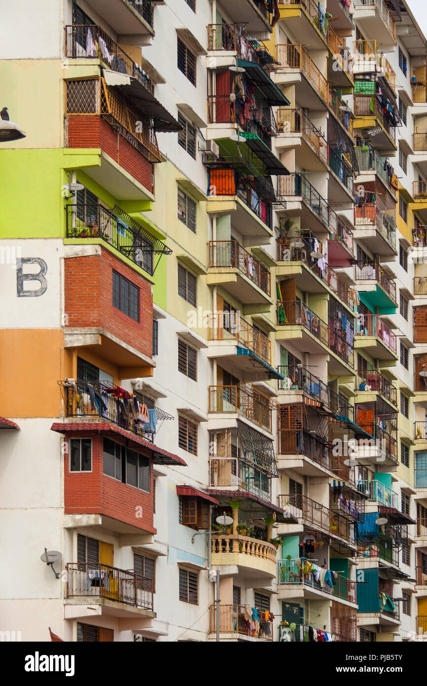 Close-up of a low cost flat in Malaysia. The colourful facade with its bright paints, different balconies and hanging clothes makes it interesting. Stock Photo