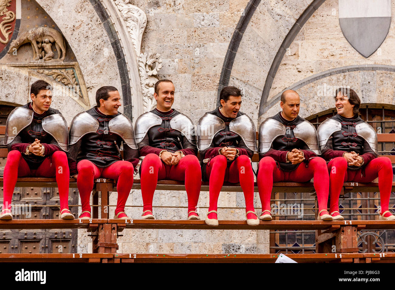 A Group Of Local Men Dressed In Medieval Costume Sit On Bleachers In