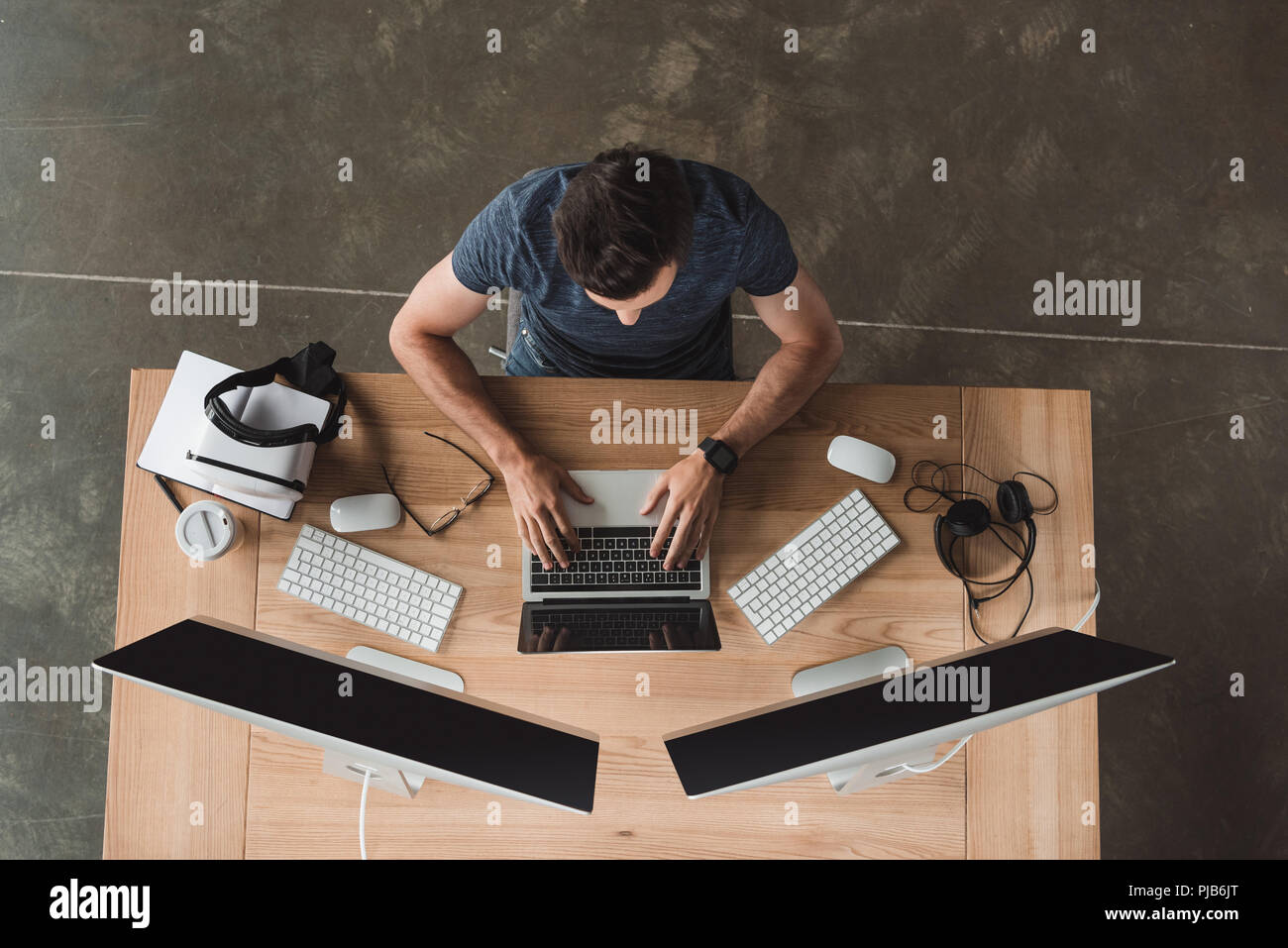 overhead view of young programmer using laptop and desktop computers at workplace Stock Photo