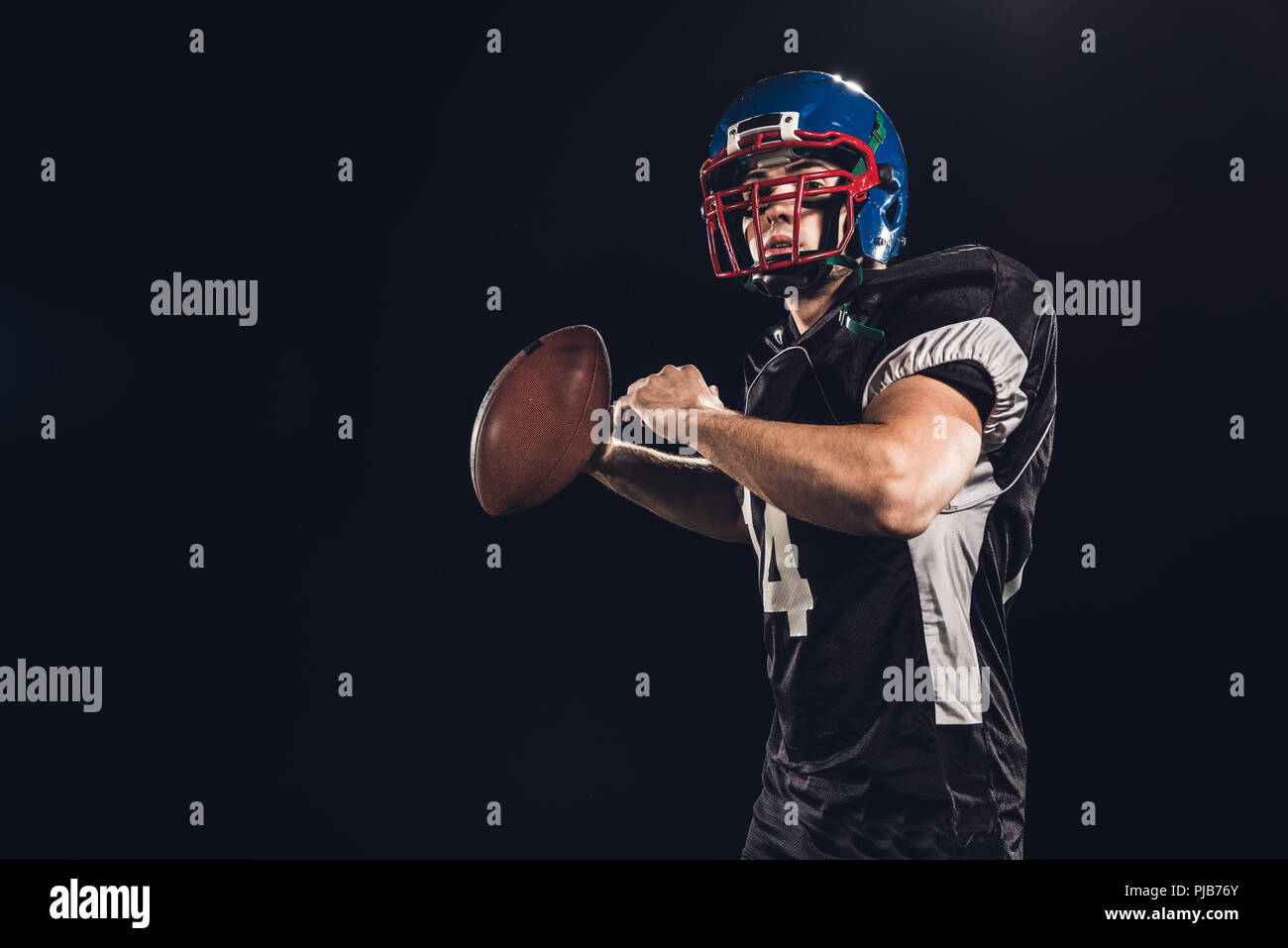 american football player throwing ball isolated on black Stock Photo