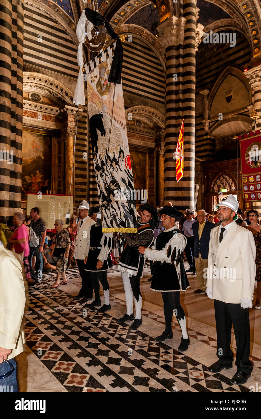 The Palio ‘Banner’ Is Carried Into The Main Cathedral As Part Of The Cero Votivo Procession, The Palio di Siena, Siena, Italy Stock Photo
