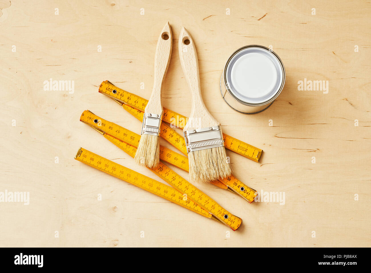 background with a ruler, paint brushes and paint cans on a wooden board Stock Photo